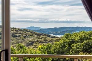 a view of the mountains from a window at Splashing Tūi Cottage in Waiheke Island