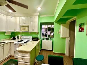 a kitchen with green walls and white cabinets at Gorgeous 1 Bedroom Gem at 7 Miles Beach Negril Point Village in Negril Aerodrome