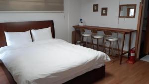 a bedroom with a bed and a table and stools at Sungsan Woori House Pension in Seogwipo
