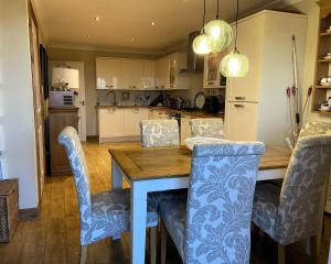 a kitchen with a wooden table and blue chairs at The Mews Llantrisant in Llantrisant