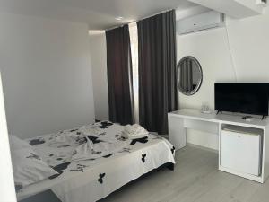 a bedroom with a bed and a desk and a television at Casa Athena in Costinesti