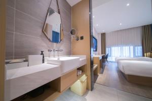 a bathroom with a sink and a bed and a mirror at Atour X Hotel Kunming Old Street Wuyi Road in Kunming +39 photos
