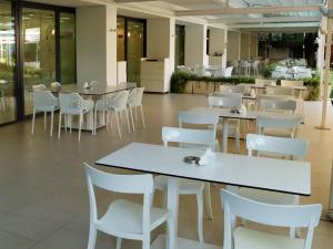 a cafeteria with white tables and white chairs at Hotel Favorit in Venus