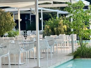 a row of white tables and chairs next to a pool at Hotel Favorit in Venus