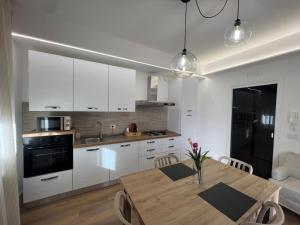 a kitchen with white cabinets and a wooden table at Ramò Apartments in Canicattì