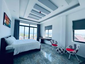 a bedroom with a bed and two chairs and windows at An Thới Ocean View - ẩn mình trên cao tầm nhìn ôm trọn biển in Phú Quốc