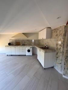 a kitchen with white cabinets and a washer and dryer at Harmony Apartments in Dhërmi
