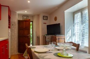 a dining room with a table and a television at La maisonnette à la caze in Saint-Pierre-des-Tripiers