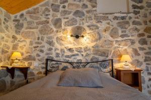 a bedroom with a stone wall with a bed and two lamps at La maisonnette à la caze in Saint-Pierre-des-Tripiers