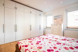 ビーレフェルトにあるGroße, zentrale Wohnung in Bielefeldのベッドルーム1室(白いキャビネット、赤い花のベッド1台付)