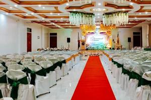 a large banquet hall with white chairs and a red carpet at RedDoorz Plus at Nick Hotel Guimba in Guimba +34 photos