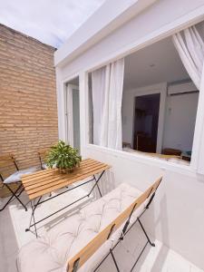 a balcony with a bench and a table and a window at Sibs Sanlucar - casita playa - coqueto vistas in Sanlúcar de Barrameda