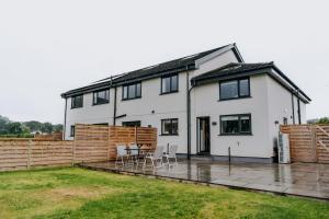 a white house with a patio and a fence at A Spacious Countryside Retreat for up to 16 Guests in Llanarthney