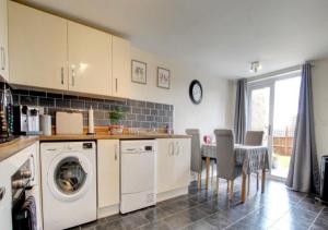 a kitchen with a washing machine and a table with chairs at Quiet and Comfortable Double guest room in Nuneaton