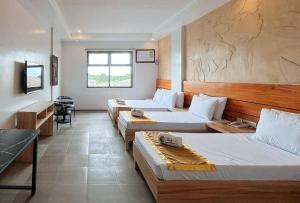 a room with three beds and a table in it at RedDoorz Plus at Nick Hotel Guimba in Guimba
