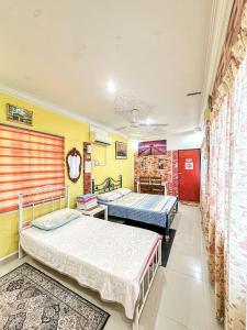 2 Betten in einem Zimmer mit gelben Wänden in der Unterkunft Dusun Indah Cottage 1 in Bayan Lepas
