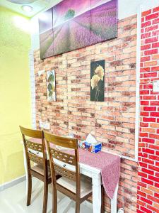 einen Tisch und zwei Stühle mit einem Tisch und einer Ziegelwand in der Unterkunft Dusun Indah Cottage 1 in Bayan Lepas