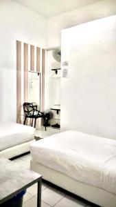 a white room with two beds and a table at Ozzy Lodge Semporna in Semporna