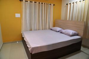 Una cama con dos almohadas encima en una habitación. en Rajendra Tourist Home, en Trivandrum 7 fotos más