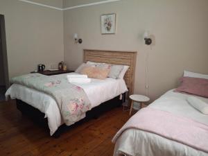 a bedroom with two beds and a wooden floor at Ruitersrust in Fauresmith