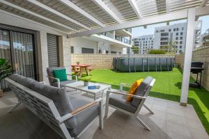 a patio with chairs and a table and a lawn at Achziv on the beach Apartment in Nahariyya