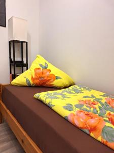 a bed with a yellow and orange blanket on it at Pension Bernburg A² in Bernburg
