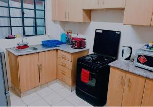 a kitchen with a black stove and wooden cabinets at MBABAZI VILLa in Syokimau