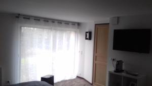 a bedroom with a large window and a television at La Gentilhommière - Chambre avec sauna et jaccuzzi in Saint-Roch