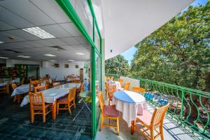 a restaurant with tables and chairs on a balcony at Hotel Zdravets in Varna City