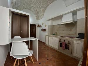 a kitchen with white cabinets and a table and chairs at La Casa della Pizzica in Ostuni