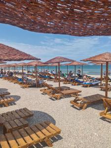 a beach with people laying on chairs and umbrellas at Hotel Gloria in Eforie Sud