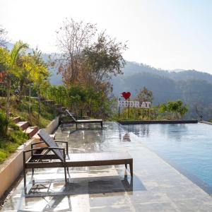 a swimming pool with benches in the middle of it at Kudrat Resort-Jim Corbett in Kota Bāgh