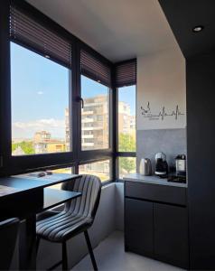 a kitchen with a table and a chair and windows at Апартамент с една спалня в ценъра на града in Yambol