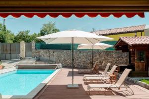 a swimming pool with two chairs and an umbrella at Trieste - Villa Prosecco in Prosecco