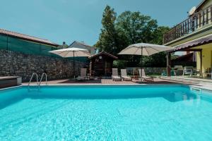 a swimming pool with chairs and umbrellas at Trieste - Villa Prosecco in Prosecco
