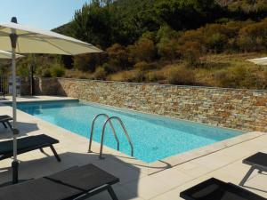 ein Swimmingpool mit Sonnenschirm und Steinmauer in der Unterkunft Appartement Candella 3 chambres in Galeria