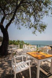 a table and chairs under a tree near the ocean at Bunaglows Panoramic Beach Village in Balchik