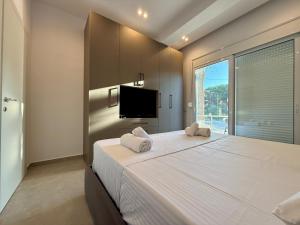 a bedroom with a large white bed with a large window at Vlora forest Apartments in Vlorë