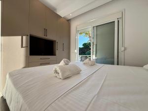 a bedroom with a large white bed with towels on it at Vlora forest Apartments in Vlorë