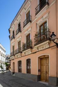a pink building with balconies on a street at Genteel Home Zaragoza in Seville