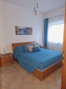 Un dormitorio con una cama con sábanas azules y una ventana. en La Casa di Taty, en Campagnano di Roma