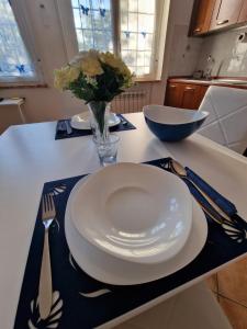 una mesa con un plato blanco y un jarrón de flores en La Casa di Taty, en Campagnano di Roma