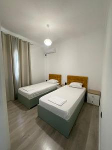 a room with two beds and a light fixture at A&K Apartments in Sarandë