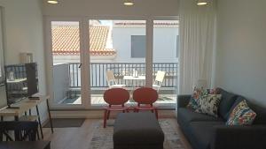 ein Wohnzimmer mit Couch und Tisch und ein Balkon in der Unterkunft Apartamento Sonho Sky in Ponta Delgada