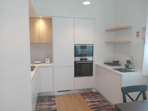 a white kitchen with a sink and a microwave at Apartamento Sonho Sky in Ponta Delgada