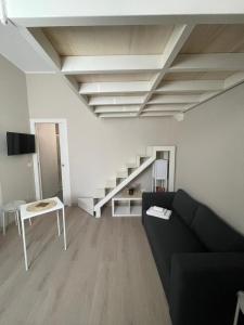 a living room with a black couch and a staircase at Le Casette by Freshome in Turin
