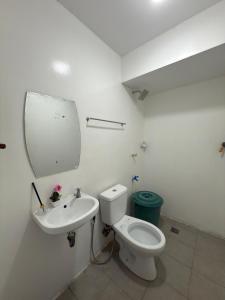 a white bathroom with a toilet and a sink at Villa Ebarle Diving Resort in Mabini