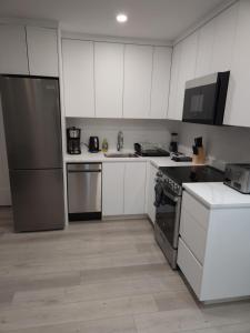 a kitchen with white cabinets and stainless steel appliances at vistaeast 1-Bedroom Condo Rupert st in Vancouver