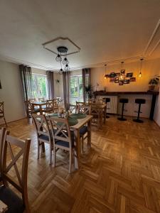 a dining room with wooden floors and tables and chairs at Willa Krynica in Krynica Zdrój