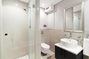 a white bathroom with a sink and a toilet at Eden on the Bay 190 by Host Agents in Cape Town +21 photos